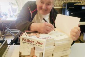 Father Joe Carroll signing copies of Father Joe Life Stories of a Hustler Priest by Kathryn Cloward.San DIego, California